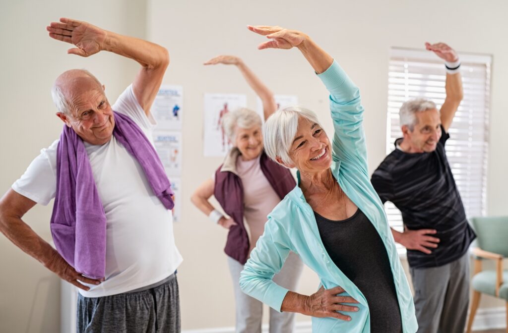 A group of seniors stretching their arms while exercising together in senior living.